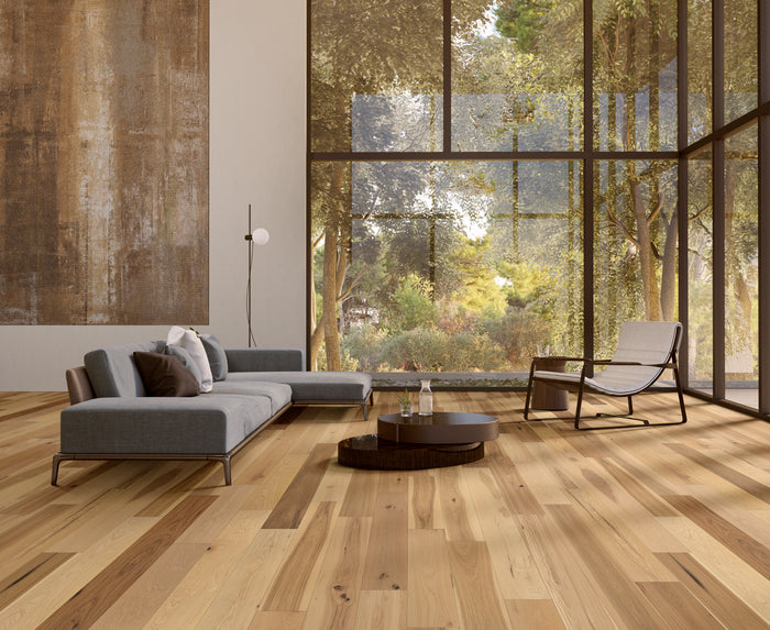 Modern living room with wooden flooring, gray sofa, and large windows.